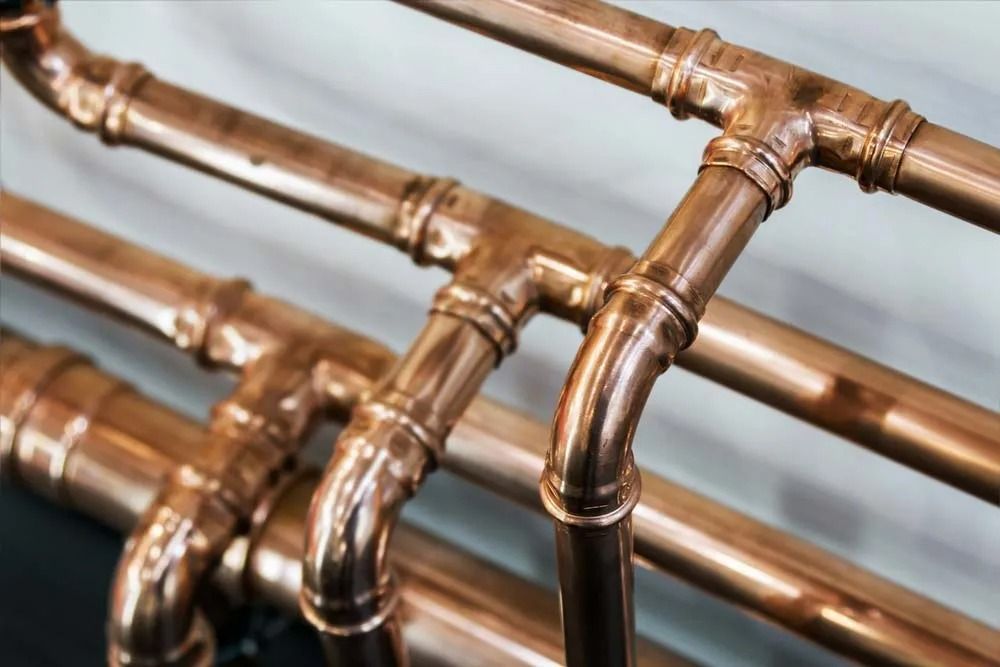 A Close-up View of Polished, Connected Copper Pipes — Dunnrite Plumbing Services in Cannonvale, QLD