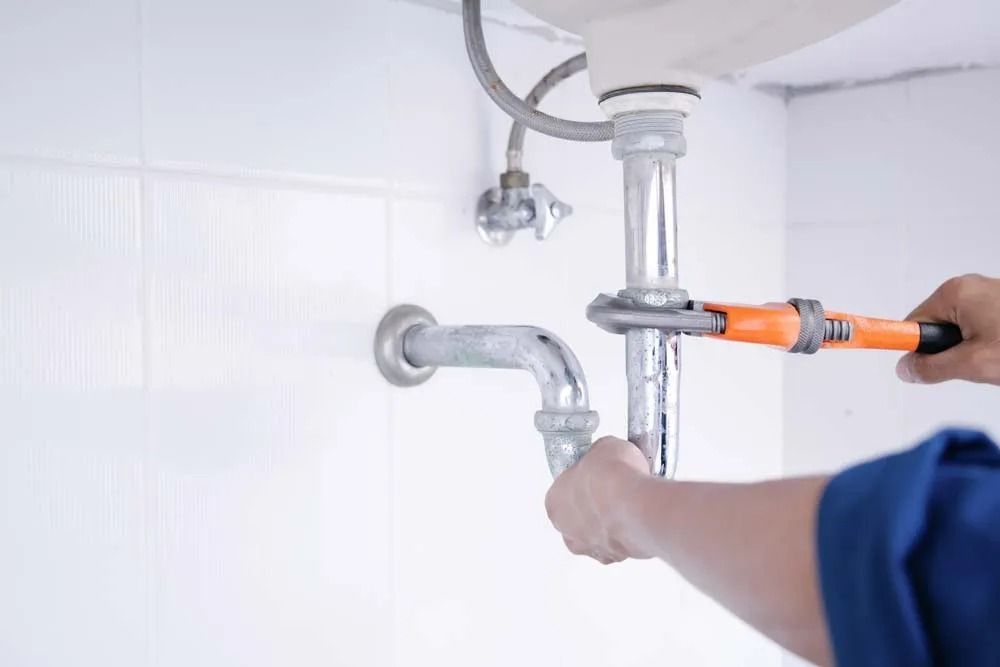 A Plumber I Uses an Orange Pipe Wrench to Tighten a Metal Pipe — Dunnrite Plumbing Services in Cannonvale, QLD