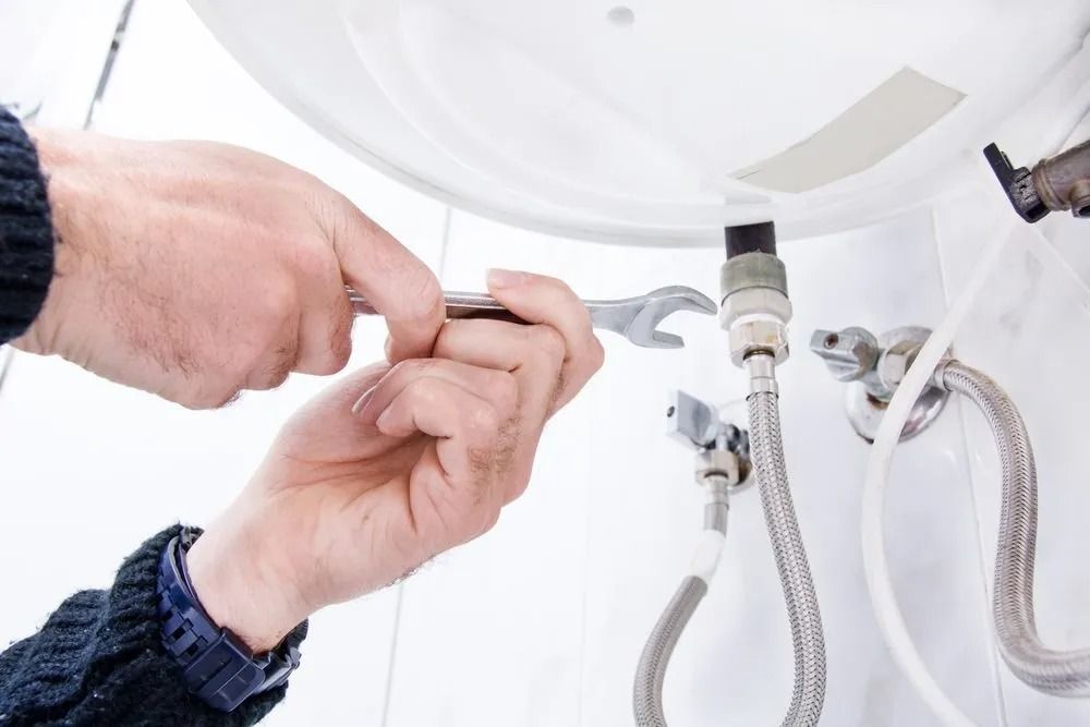 A Pair of Hands Using a Wrench — Dunnrite Plumbing Services in Cannonvale, QLD