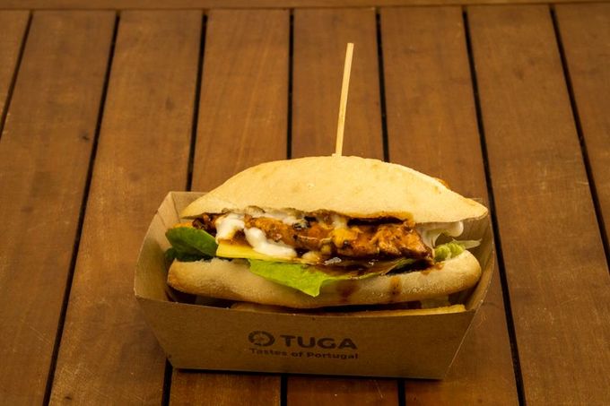 A sandwich is sitting in a cardboard box on a wooden table — O Tuga Tastes Of Portugal In Melbourne, VIC