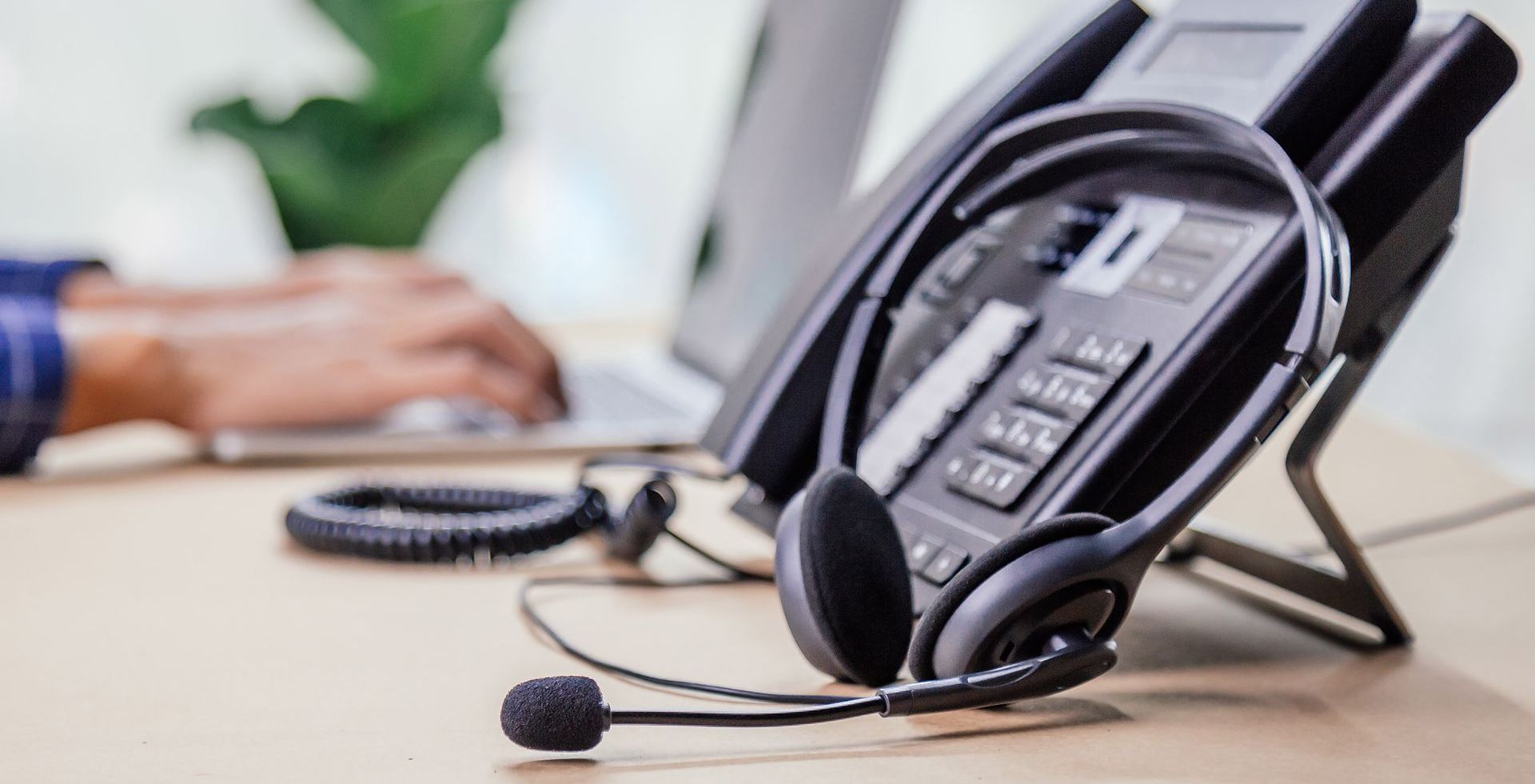 A close up of a telephone with a headset on a desk.