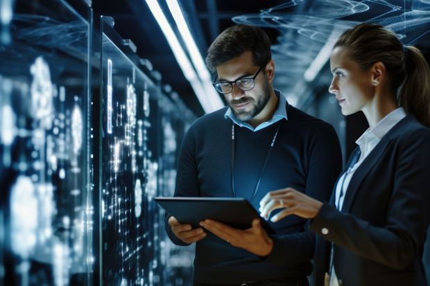 a man and a woman are looking at a tablet in a server room .