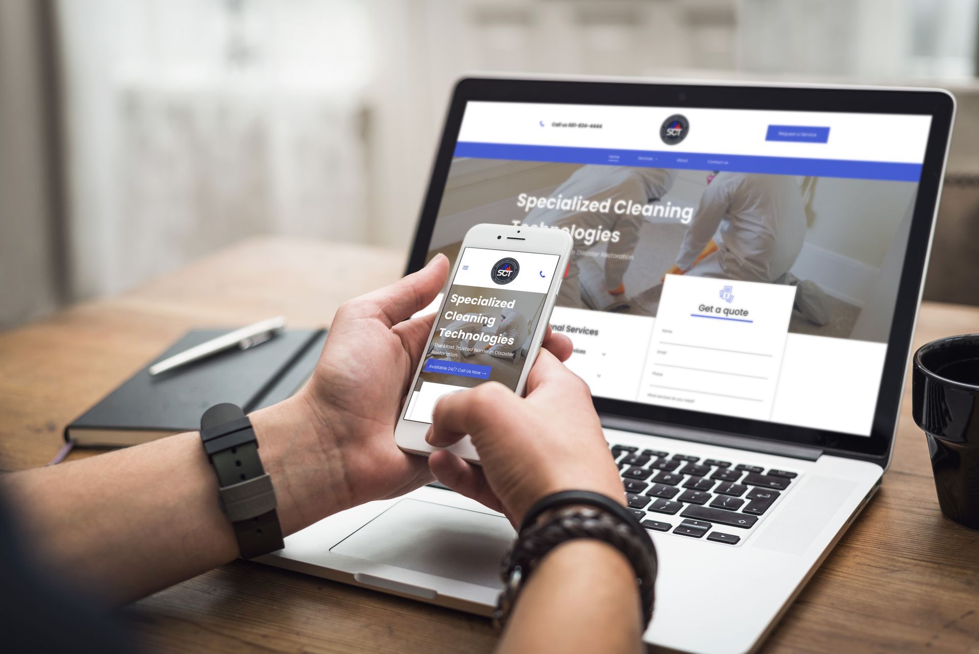 A person holding a cell phone in front of a laptop viewing the Specialized Cleaning Technologies website