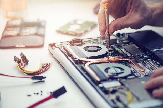 a person is working on a laptop computer with a screwdriver .