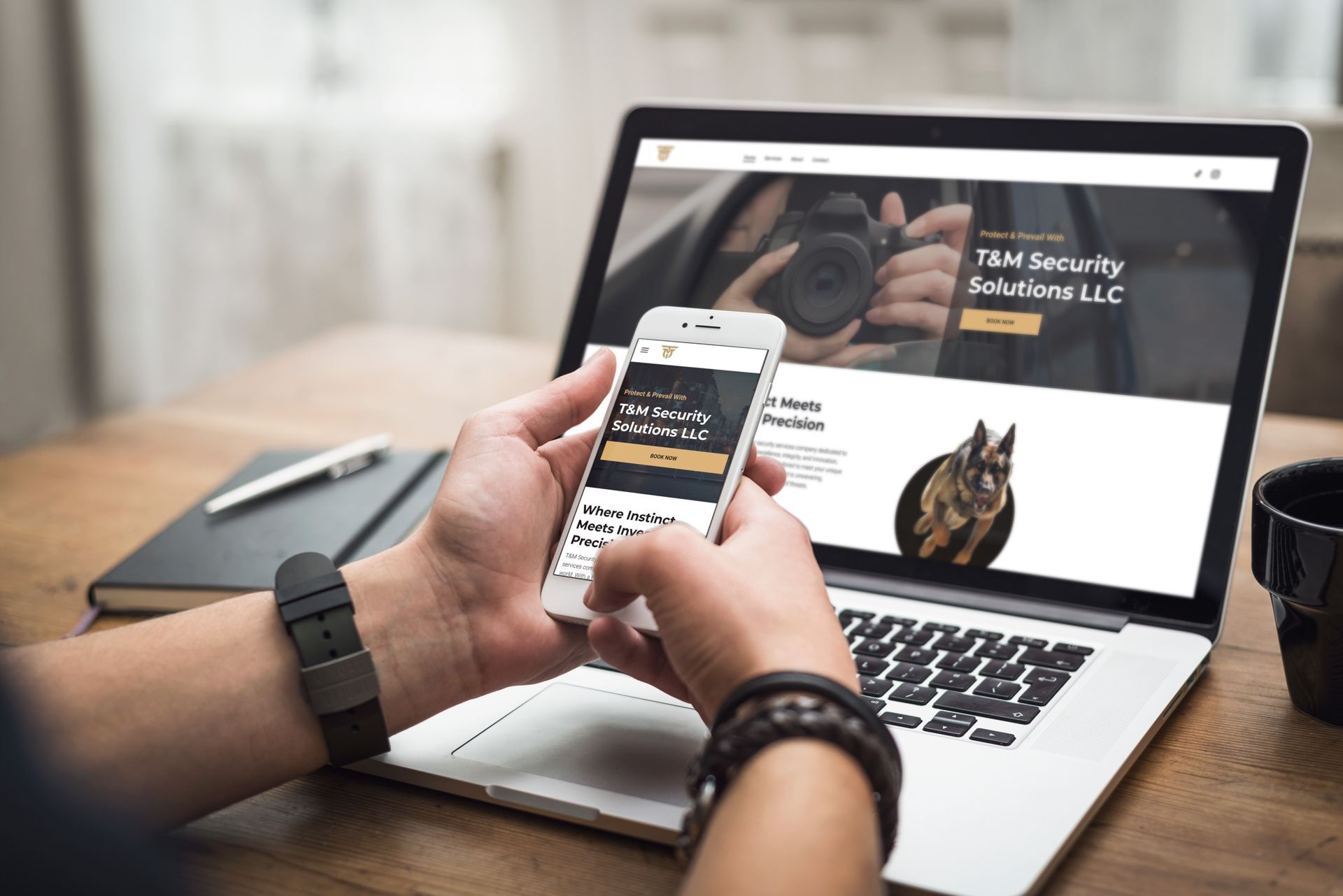 A person holding a cell phone in front of a laptop viewing the T&M Security Website