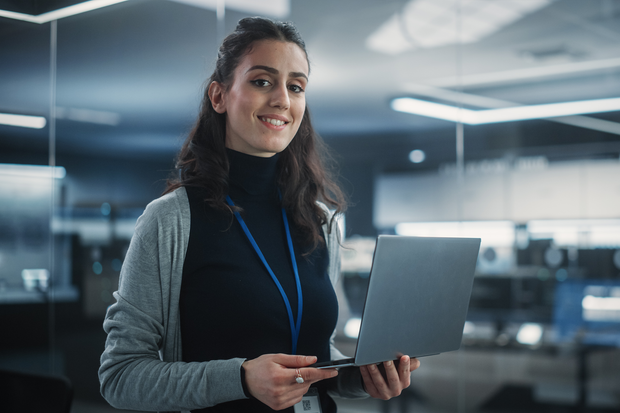 a woman is holding a laptop computer in her hands and smiling .