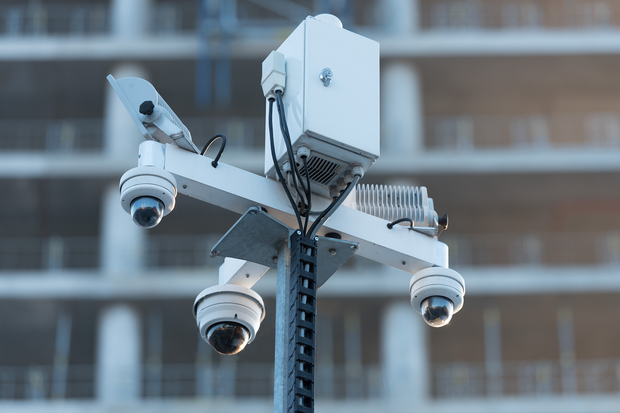 a row of security cameras on a pole in front of a building .