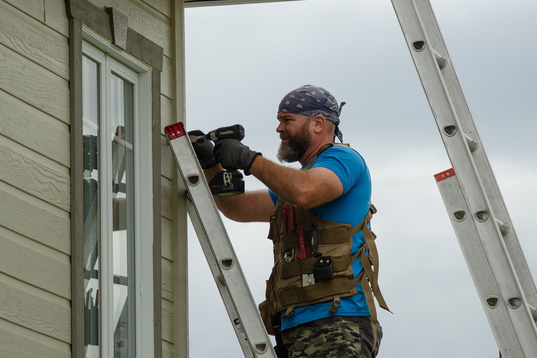 Un homme est debout sur une échelle et travaille sur une fenêtre.