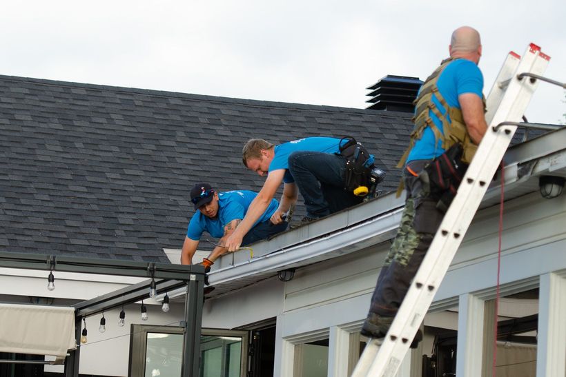 Un groupe d'hommes travaillent sur le toit d'une maison.