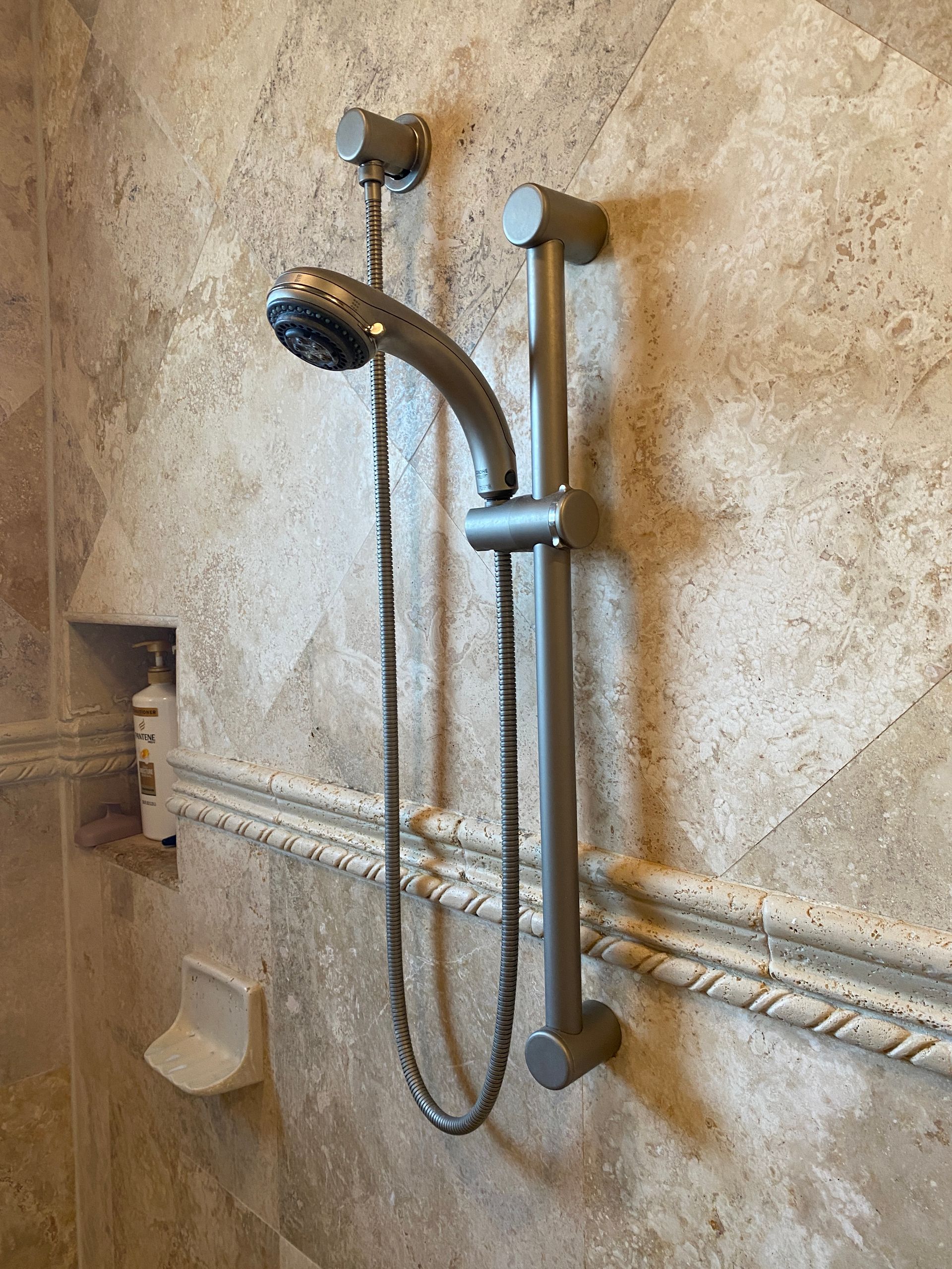 A shower head is hanging on a tiled wall in a bathroom.