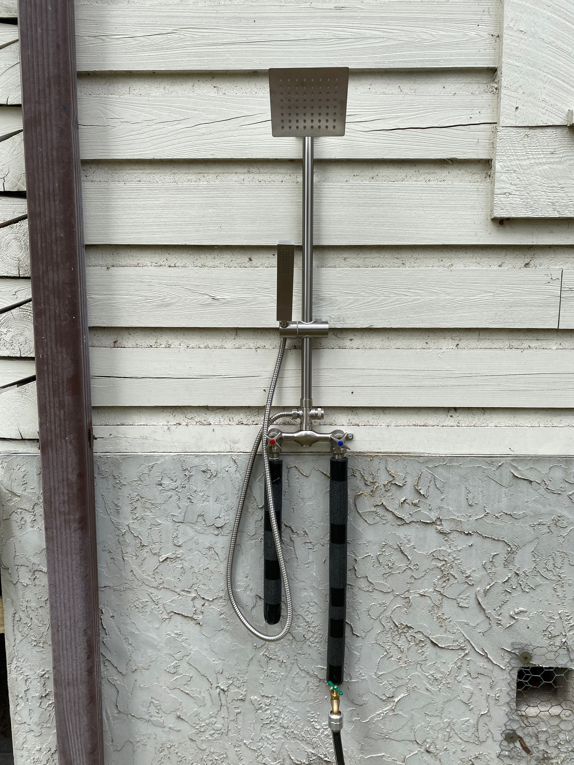 A shower head is attached to the side of a building.