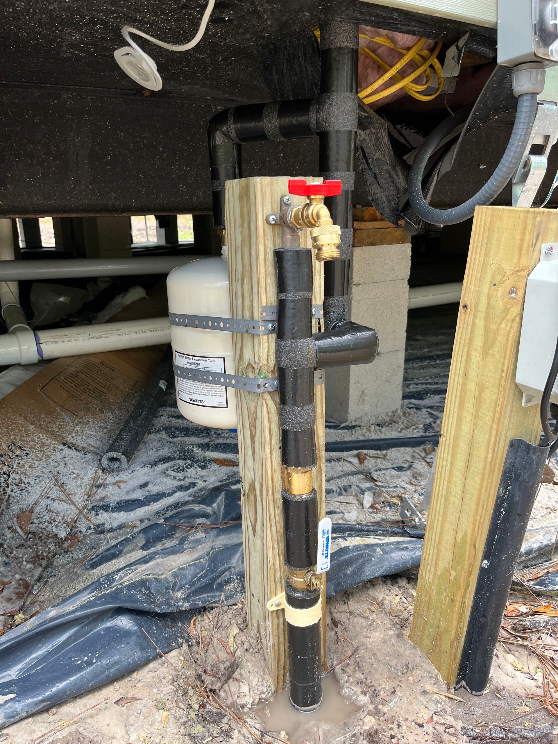 A water pump is attached to a wooden post.