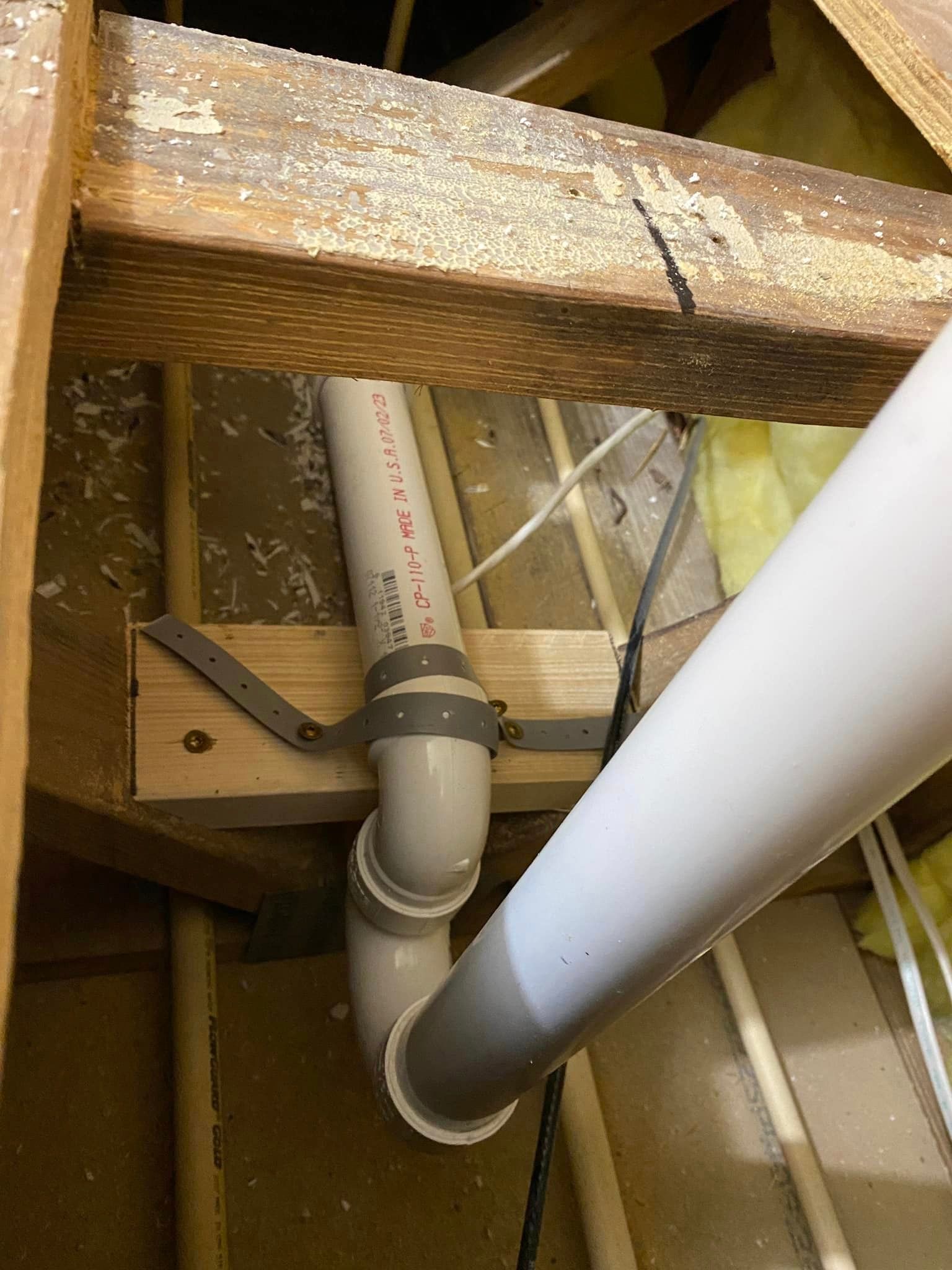 A white pipe is sitting under a wooden beam in a room.