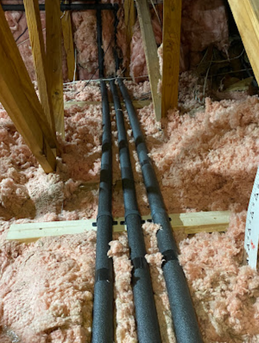 A bunch of pipes are hanging from the ceiling of a building.
