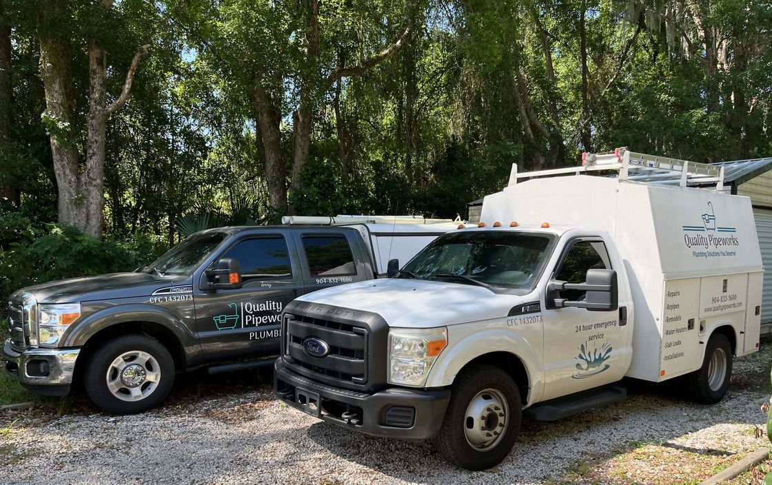 Two trucks are parked next to each other in a gravel lot.