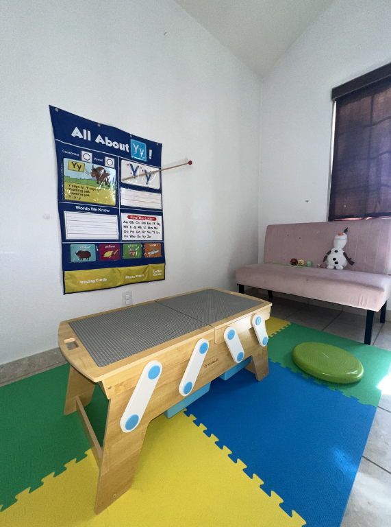 Indoor playroom with a toddler balance beam, foam mats, cushioned bench, and wall poster