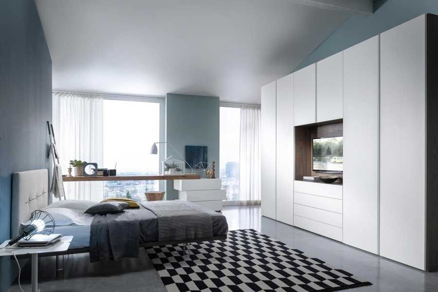 Camera da letto moderna con grande armadio bianco, letto e tappeto a fantasia bianca e nera.