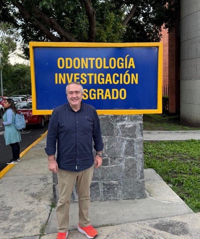 Hombre de pie frente a un letrero azul que dice
