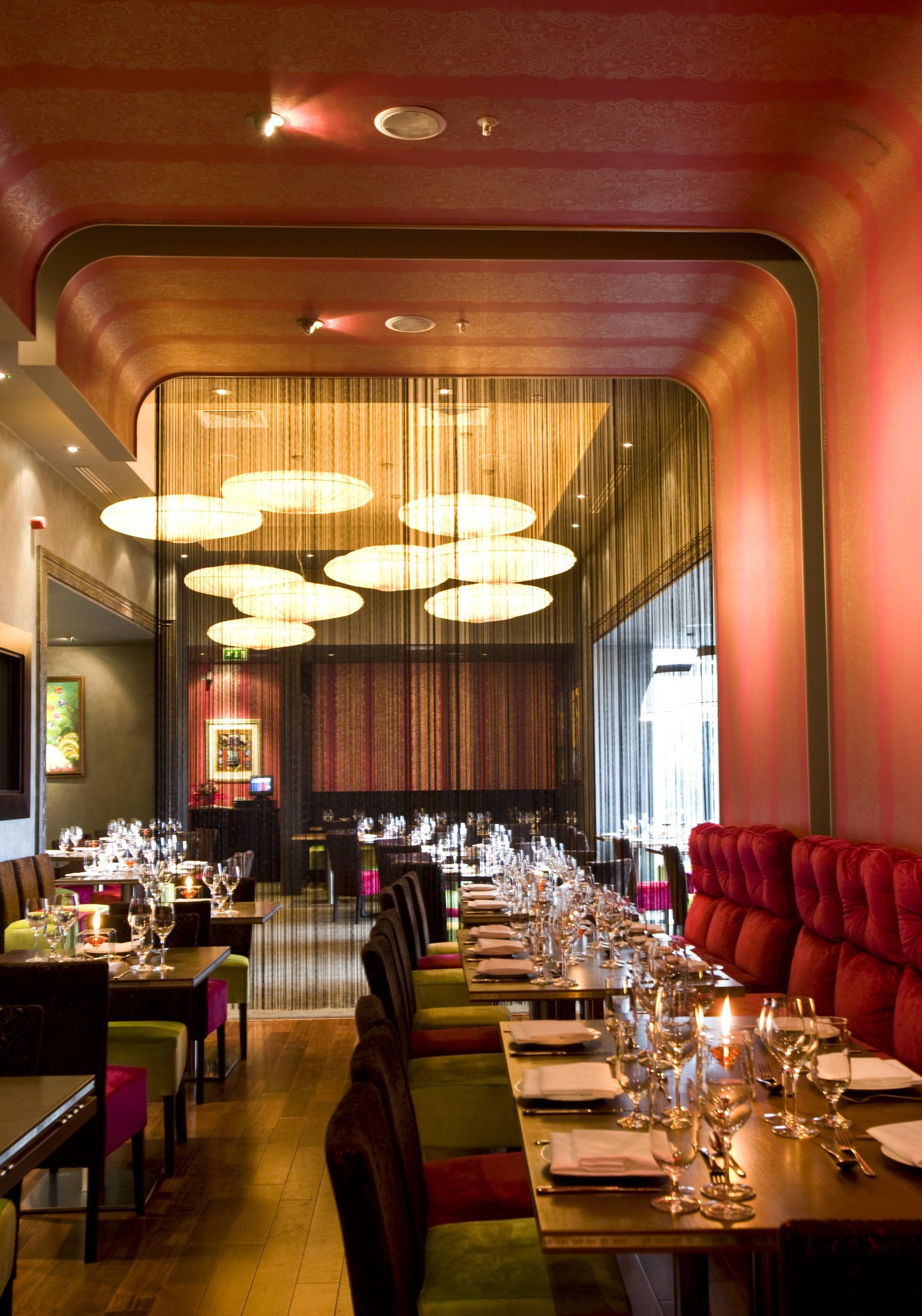 A restaurant with tables and chairs and a red ceiling