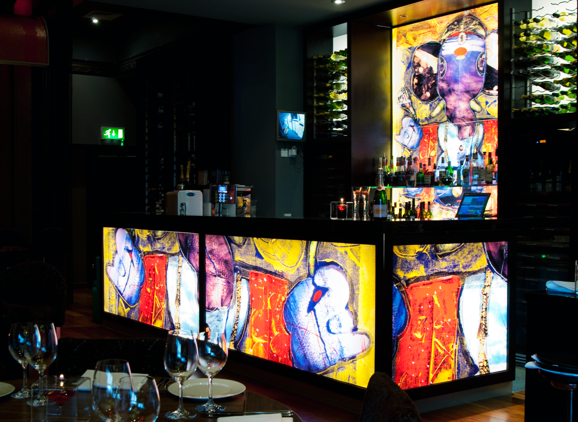 A bar in a restaurant with a painting on it