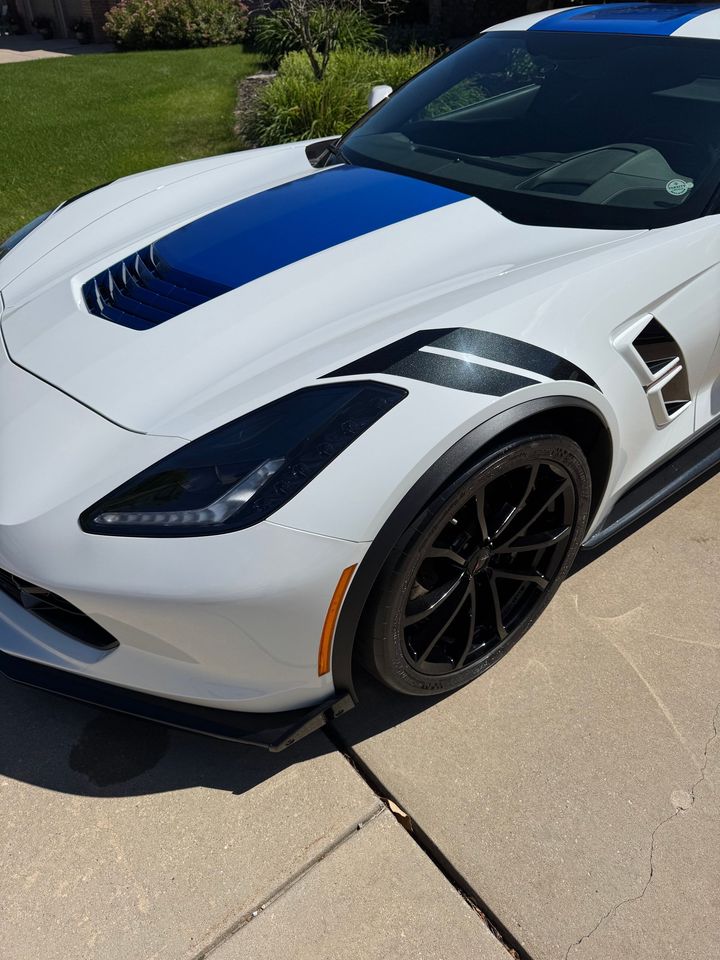A white and blue sports car is parked on the sidewalk