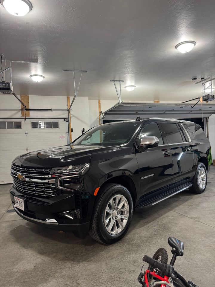 A black suv is parked in a garage next to a bike.