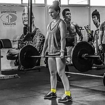 A woman is lifting a barbell in a gym.