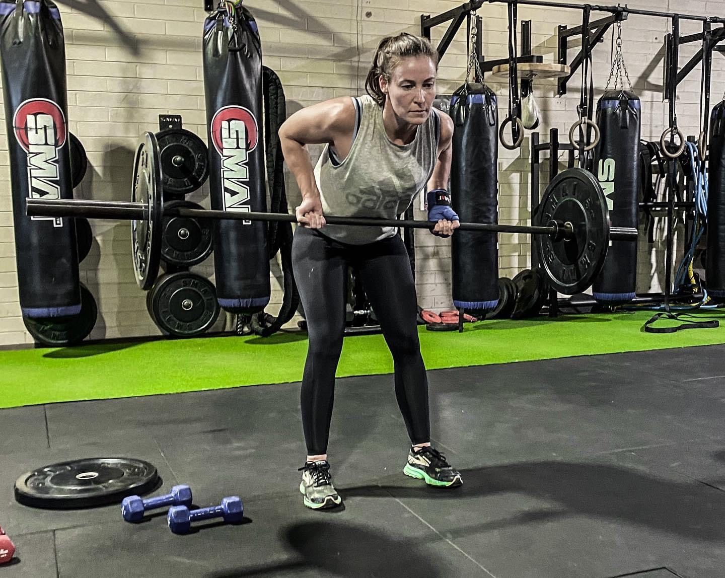 A woman is lifting a barbell in a gym.
