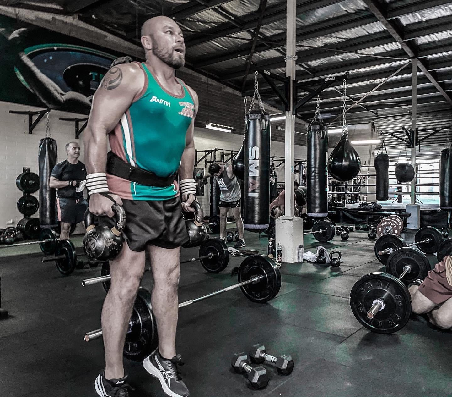 A man is lifting a barbell in a gym.