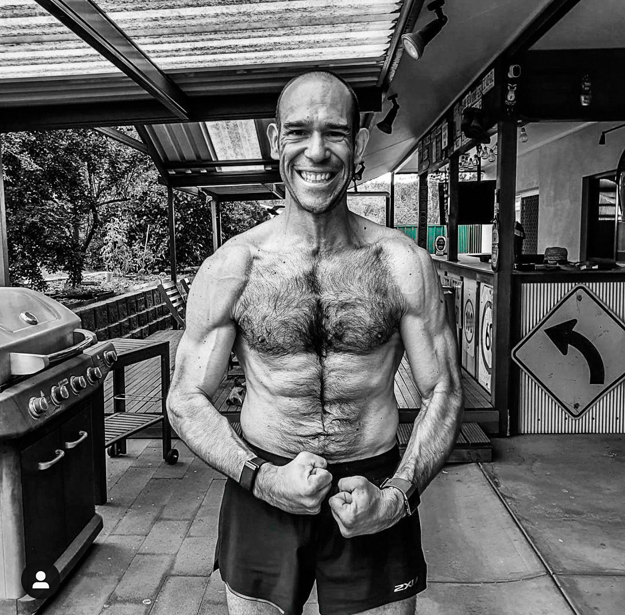 A man without a shirt is posing for a black and white photo.