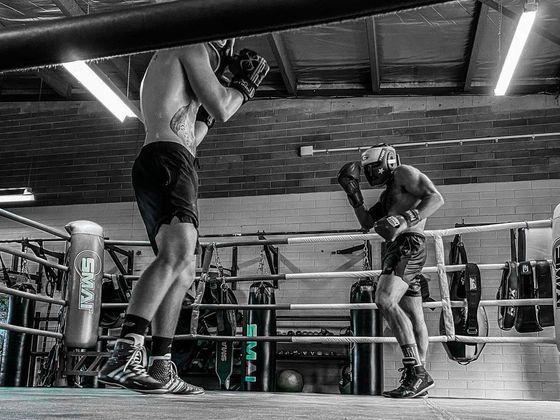 Two men are boxing in a boxing ring in a gym.