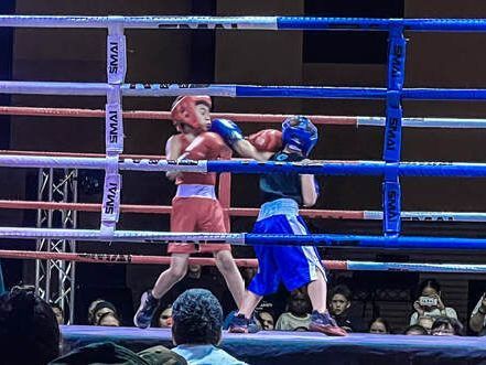 Two young boys are boxing in a boxing ring.