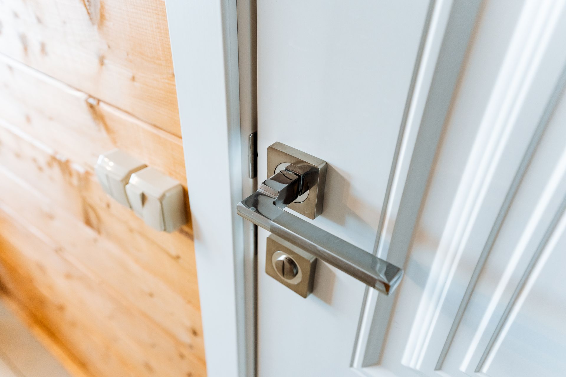 A close up of a door handle on a white door.