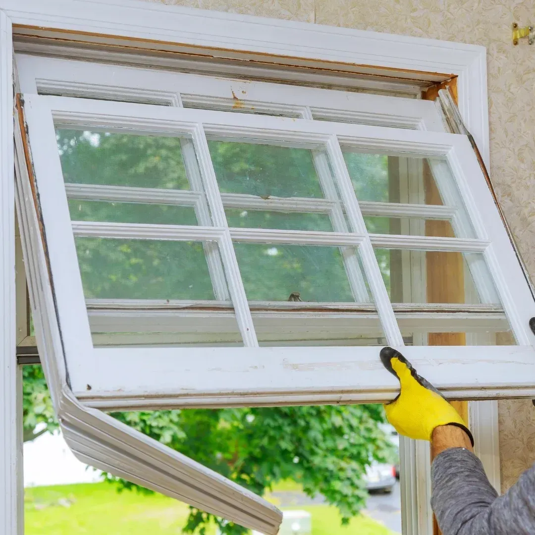Person in yellow gloves lifting a white window sash open