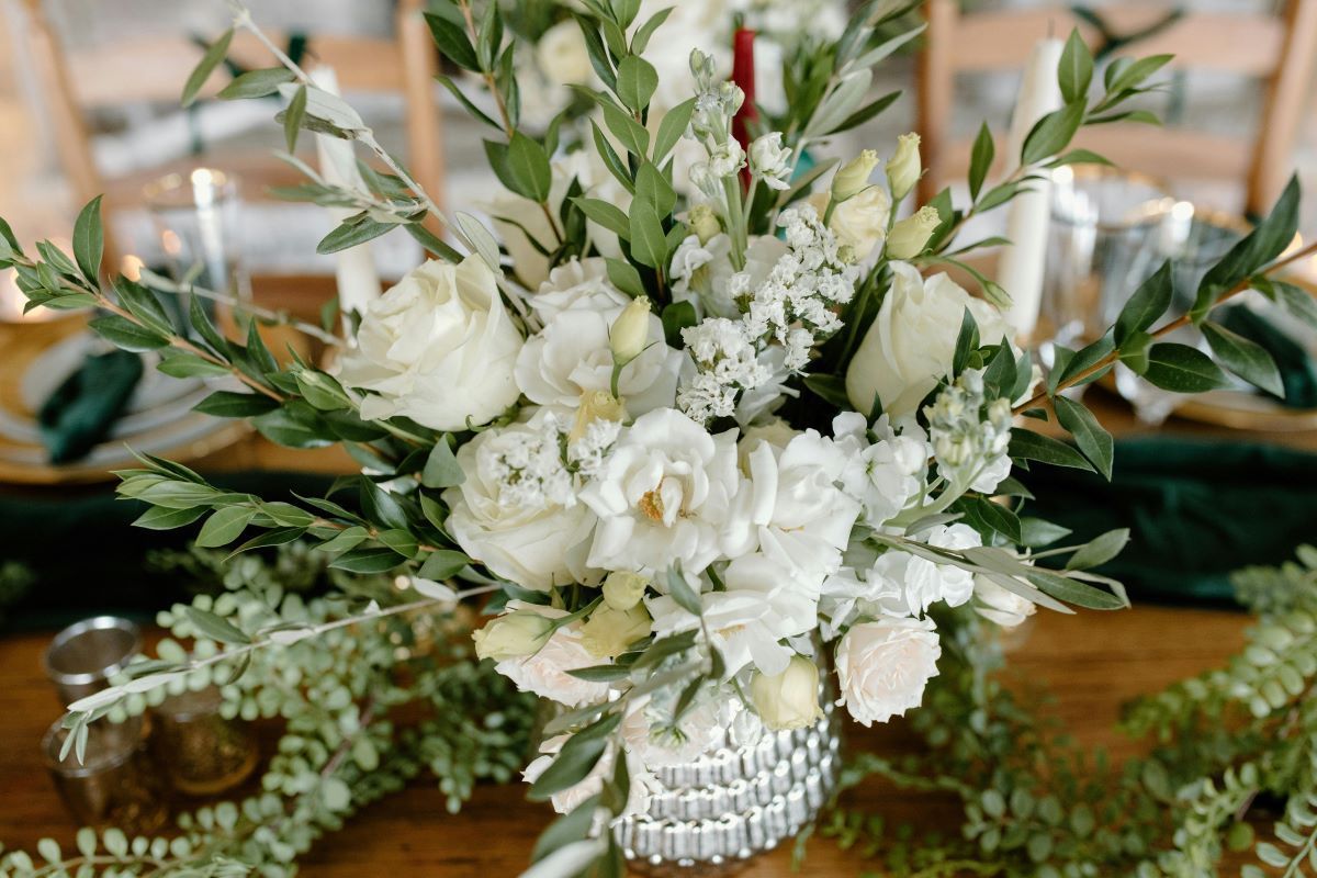 A white envelope filled with red berries is sitting on a wooden table.