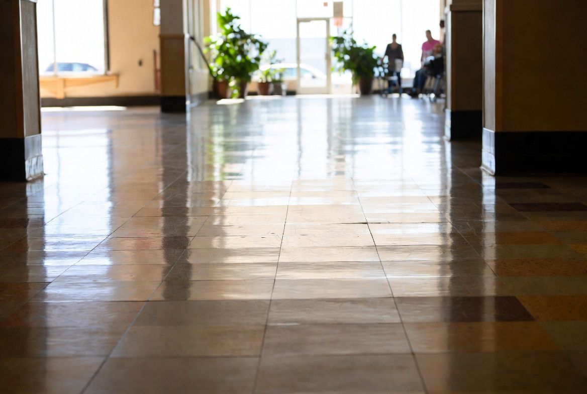Empty tiled hallway with reflections and a few people in the distant background