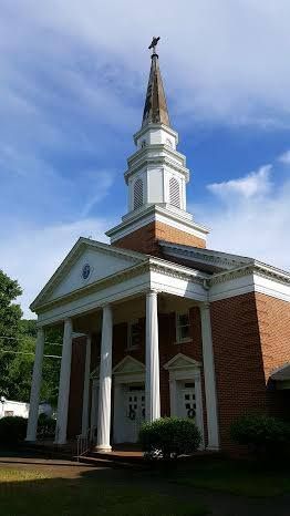 A church with a clock tower and a cross on top of it.