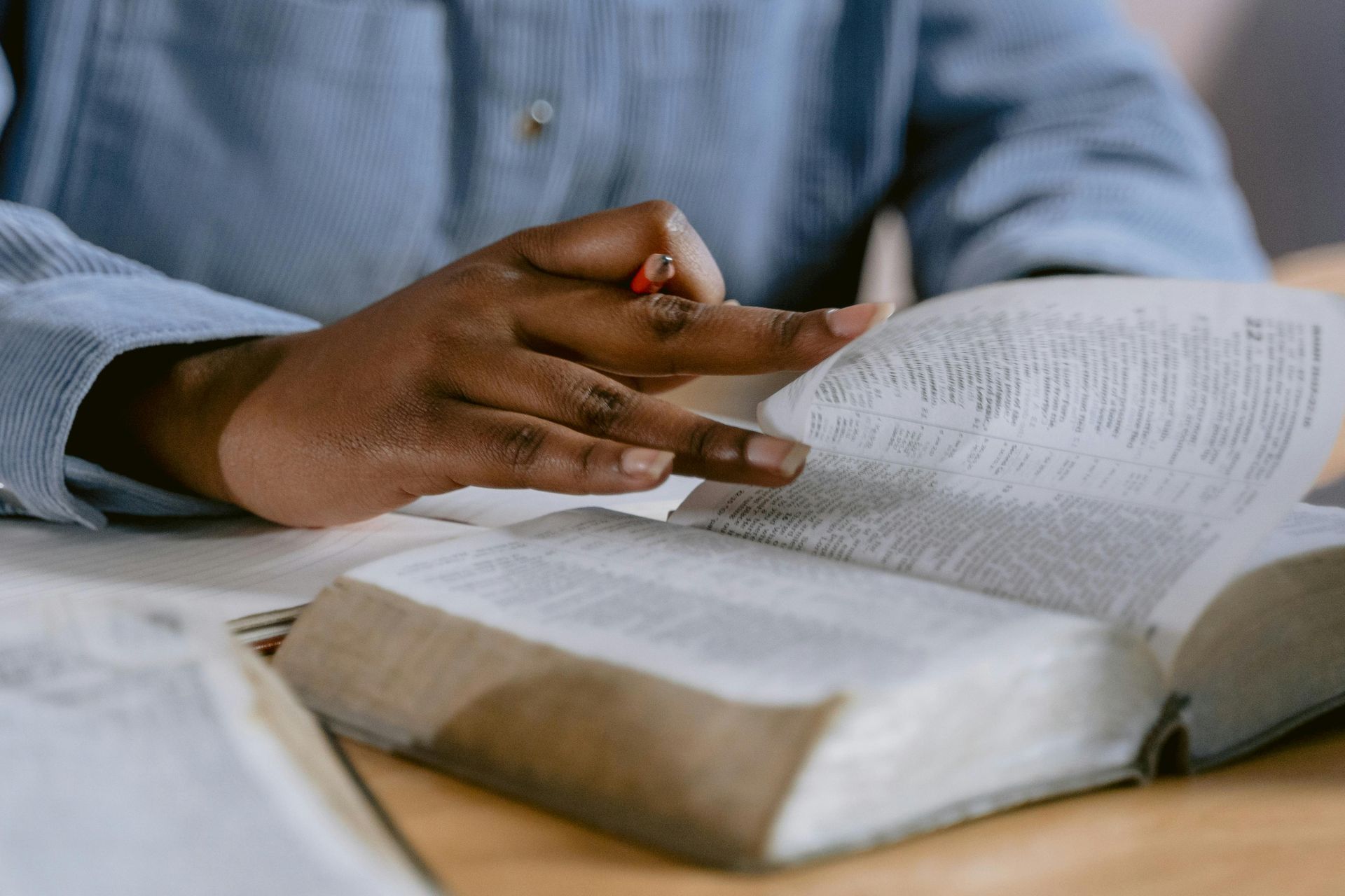 A person is sitting at a table reading a bible.