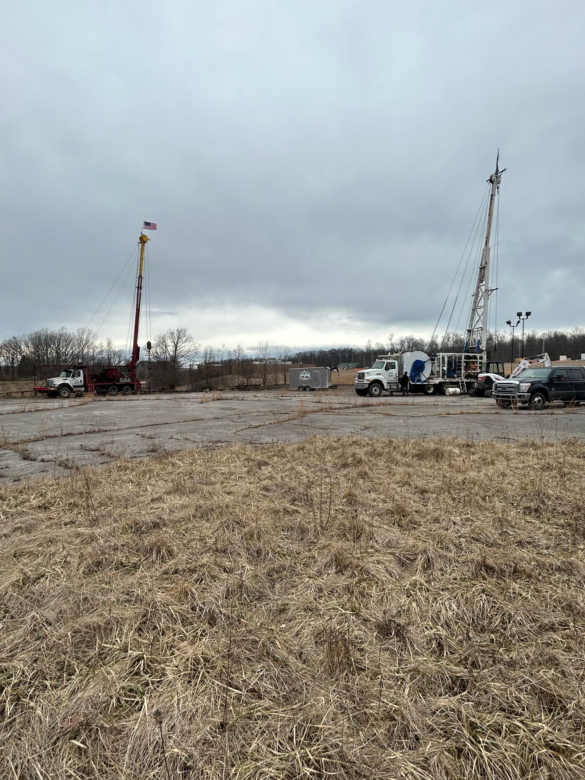 Two drilling rigs on a barren field under a cloudy sky, possibly for oil or gas exploration.