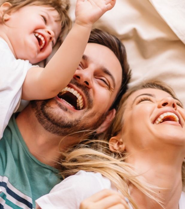 A family laughing together while lying down, viewed from above.