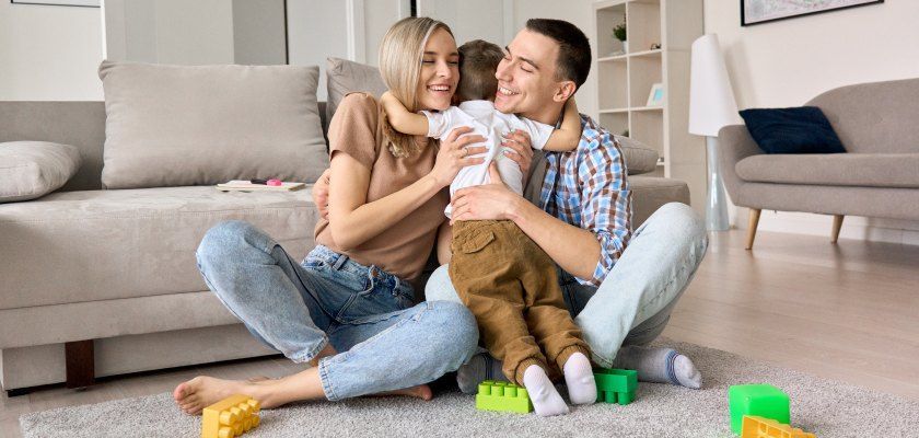 Family hugging while sitting on a floor.