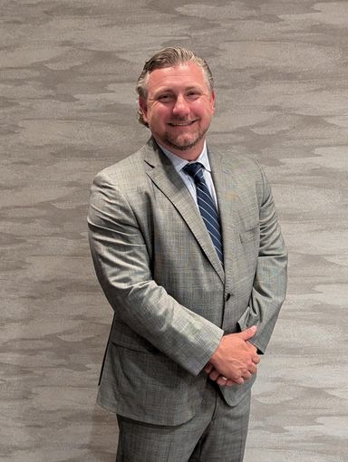 A man in a suit and tie is smiling for the camera.