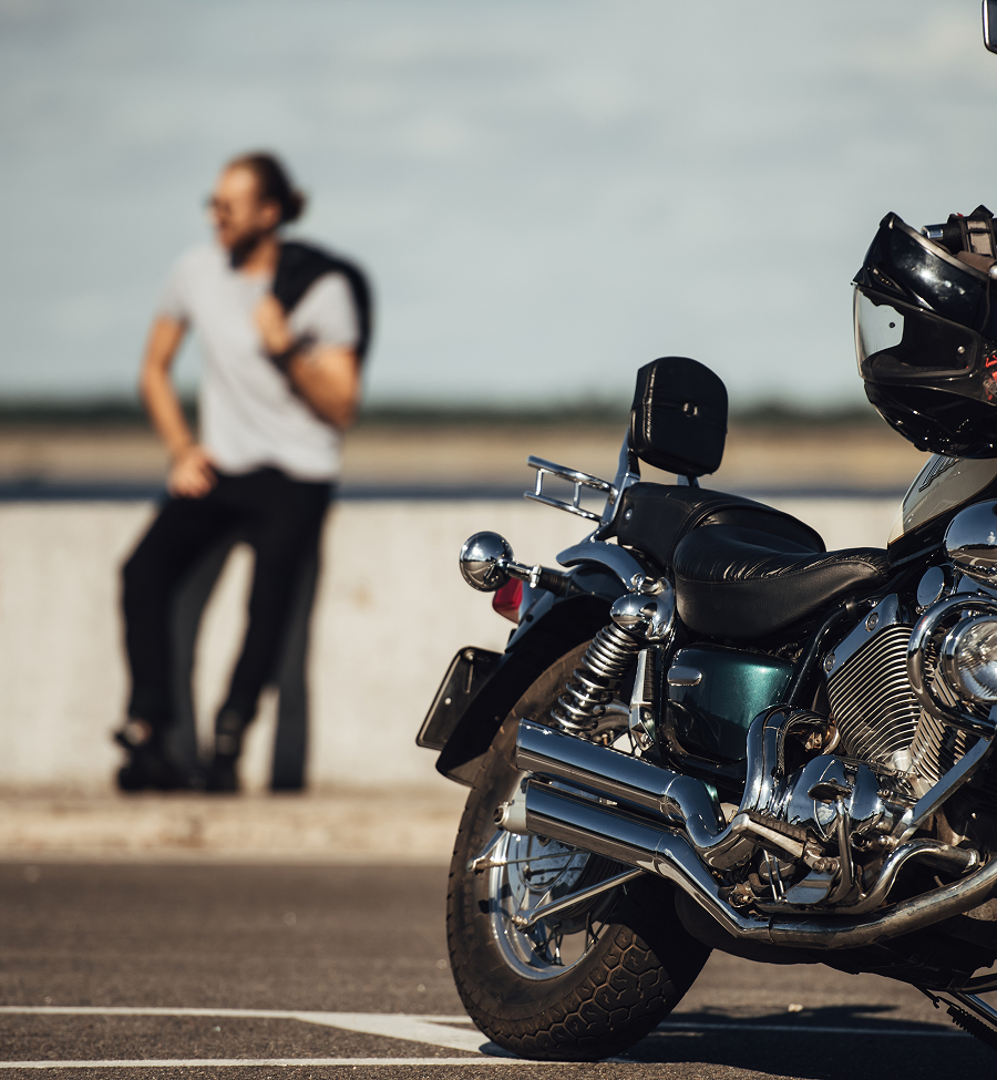 A man sits on a wall behind a motorcycle
