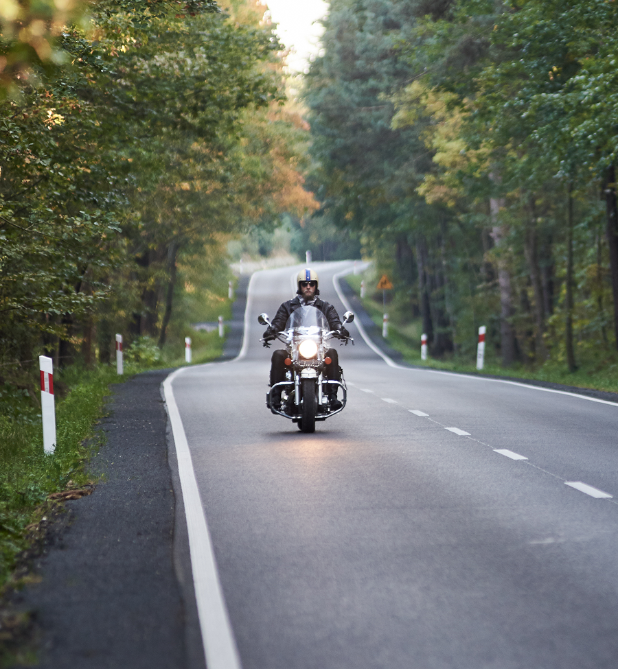 A man is riding a motorcycle down a road