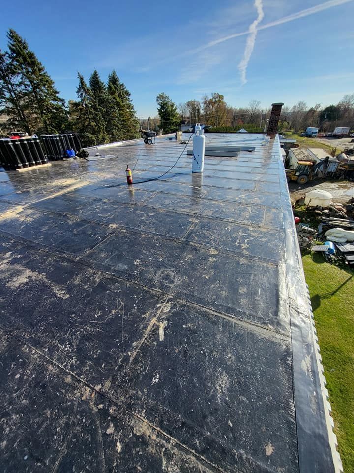 Un toit noir avec une cheminée au dessus.