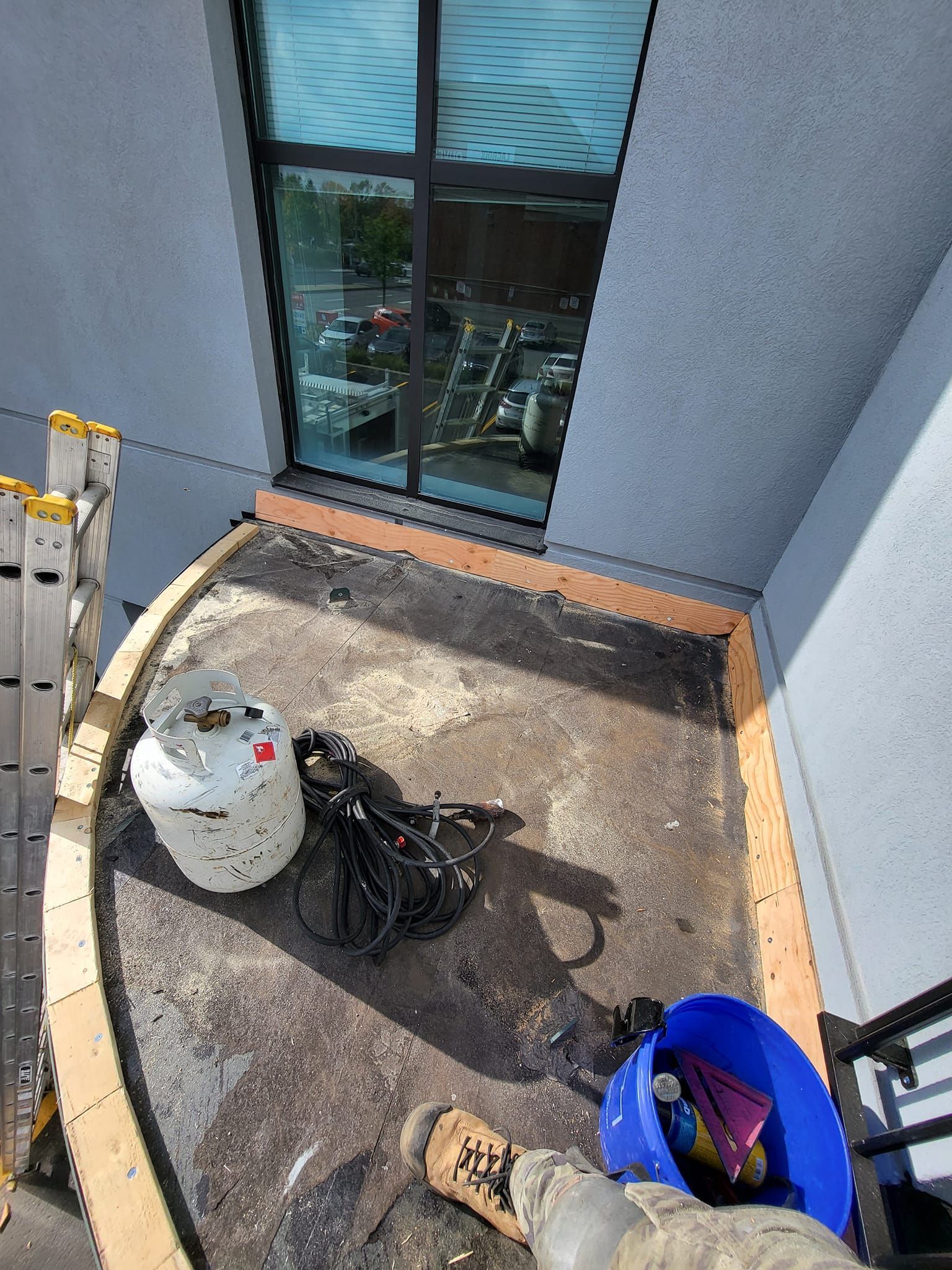 Un réservoir de propane est posé sur un balcon à côté d'une fenêtre.