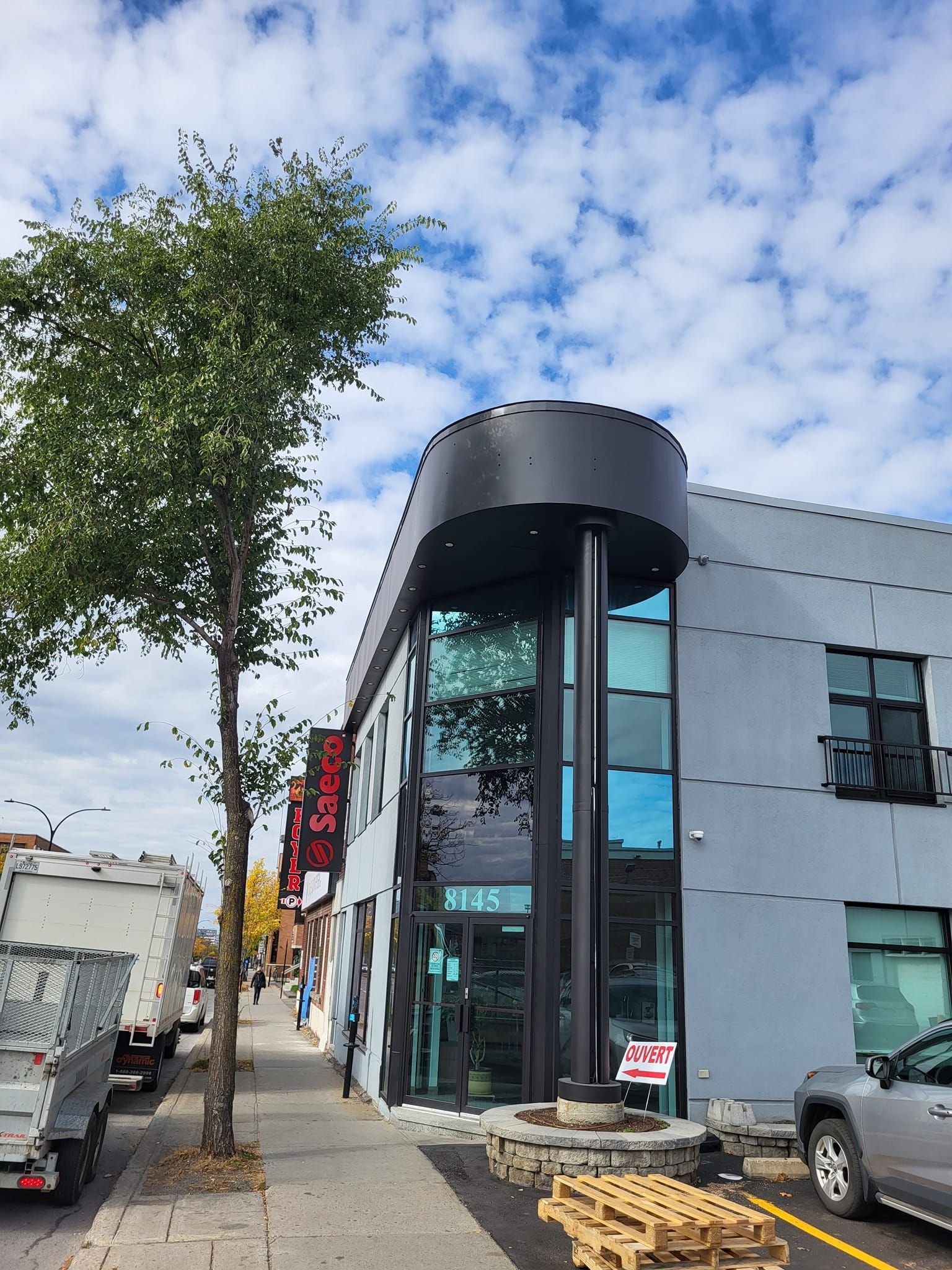 Un grand bâtiment avec beaucoup de fenêtres et un arbre devant.