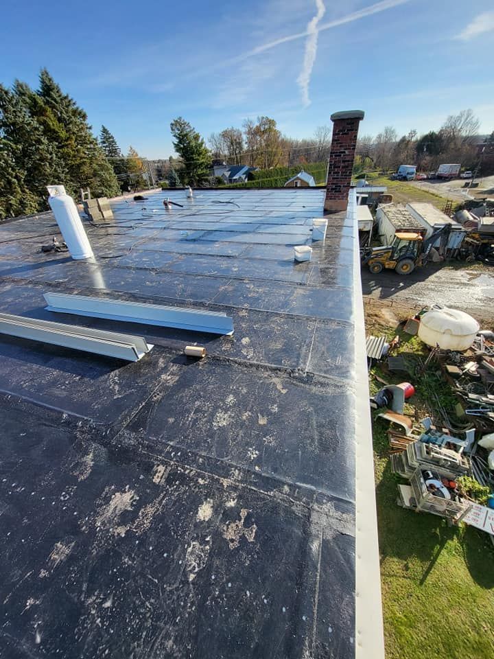 Un toit noir avec une cheminée au dessus.