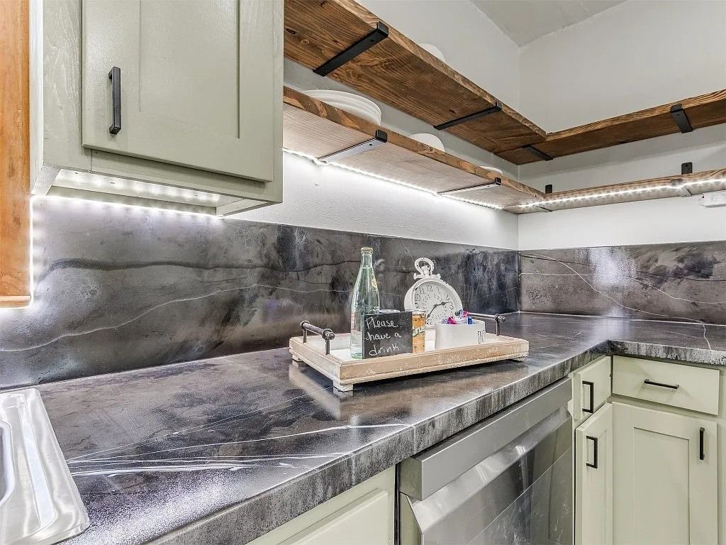 Kitchen with gray countertops, white cabinets, and wooden beams. Illuminated by LED strip lights.