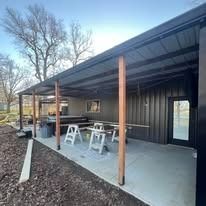 Covered outdoor space with tables, chairs, and metal siding.